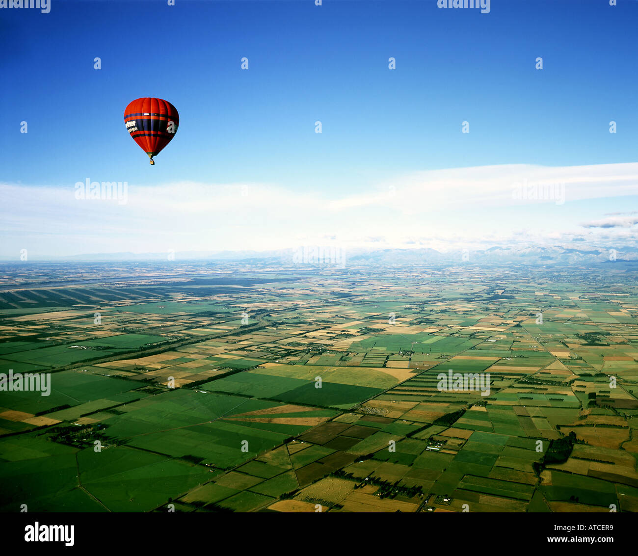 Red hot air balloon déménagement à travers les plaines près de Christchurch, Nouvelle-Zélande, île du Sud Banque D'Images