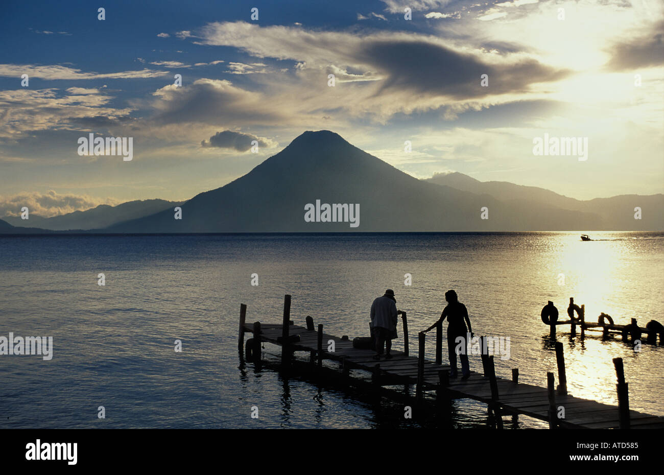 Les touristes à la fin d'une jetée qui se profile au coucher du soleil Panajachel Lac Atitlan Guatemala volcan San Pedro au-delà Banque D'Images