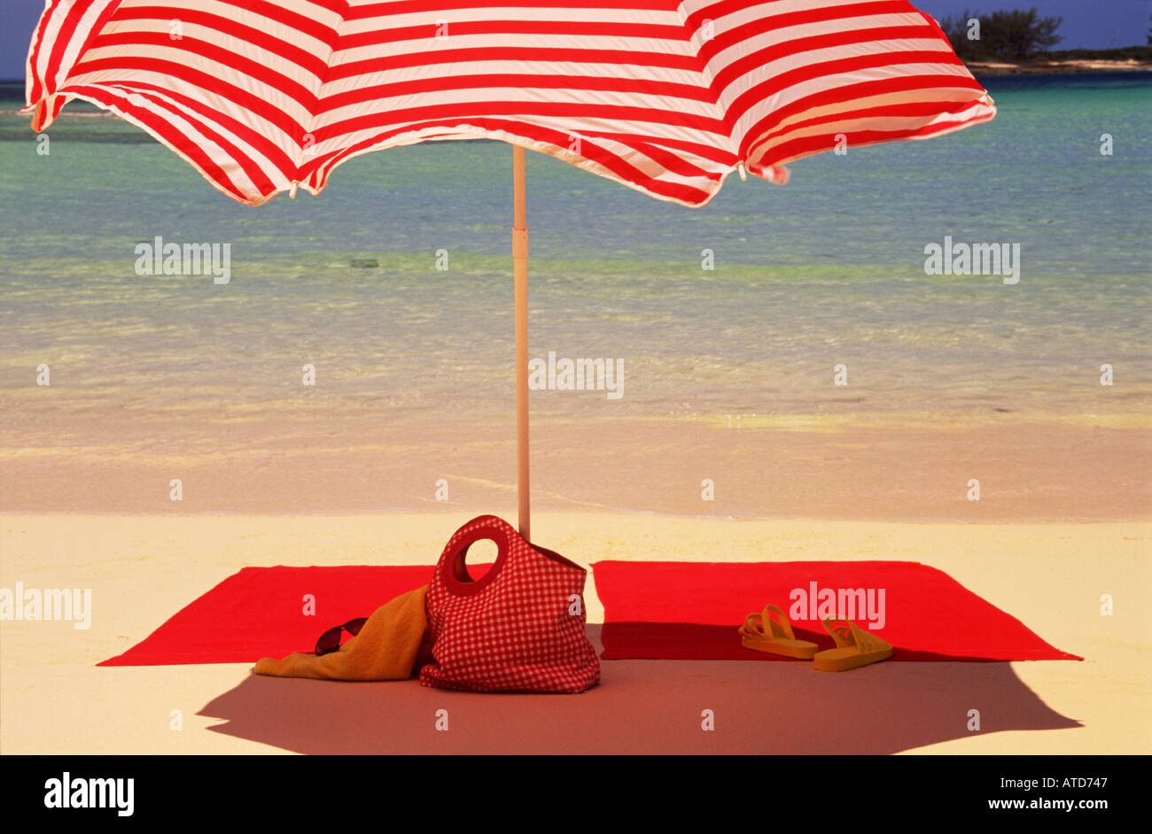 Une serviette de plage rouge rouge et blanc sous un parasol à rayures aux  Bahamas Photo Stock - Alamy