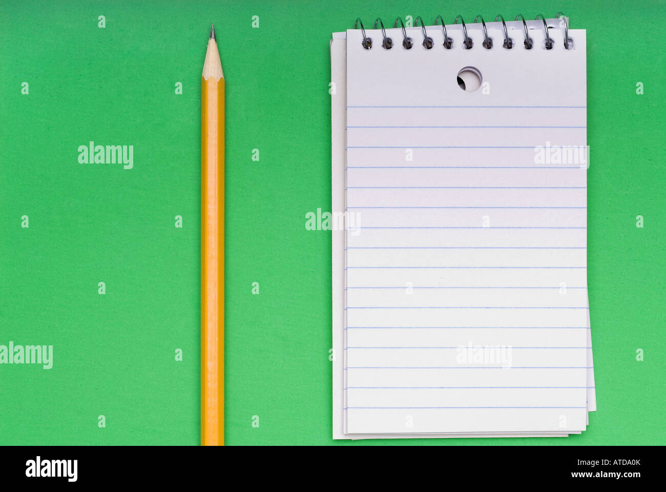 Un crayon et un bloc-notes en blanc sur un fond vert lumineux Banque D'Images