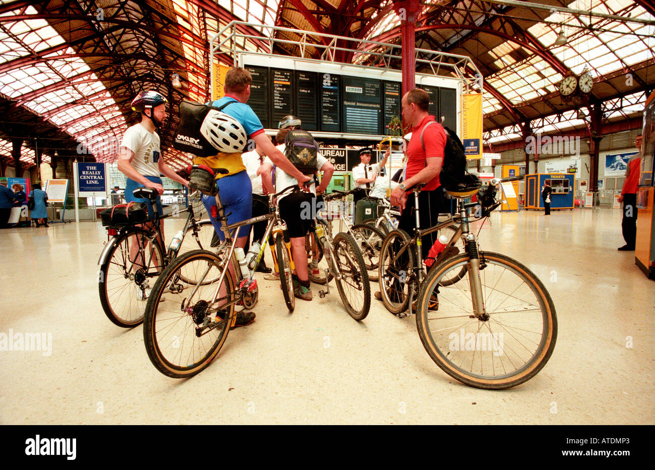 Quatre cyclistes masculins après la Londres à Brighton en vélo en attente à la gare pour un train home Banque D'Images
