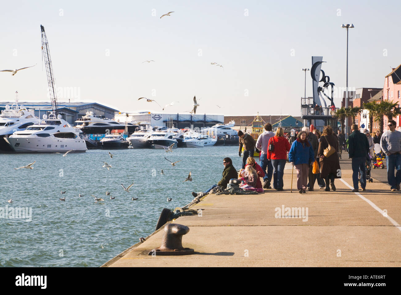 Les personnes bénéficiant de début du printemps soleil sur Poole Quay. En face est le Sunseeker yacht usine. Le Dorset. UK. Banque D'Images