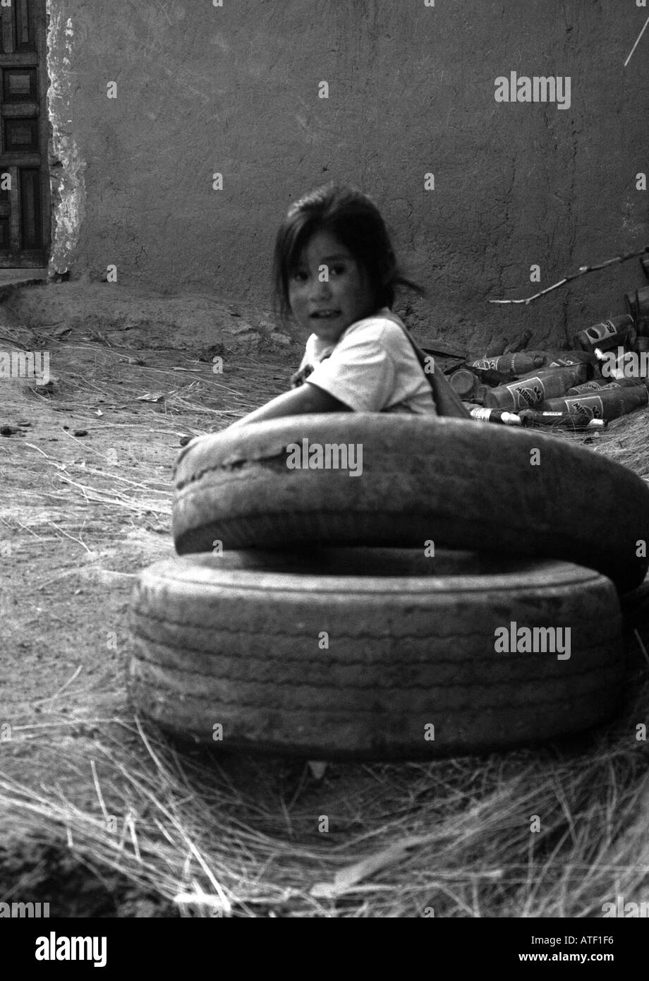 Les enfant jouer sourire fille pneu en caoutchouc au sol à l'air libre la saleté junk bouteille Vallée Sacrée Cuzco Pérou Amérique Latine du Sud Banque D'Images