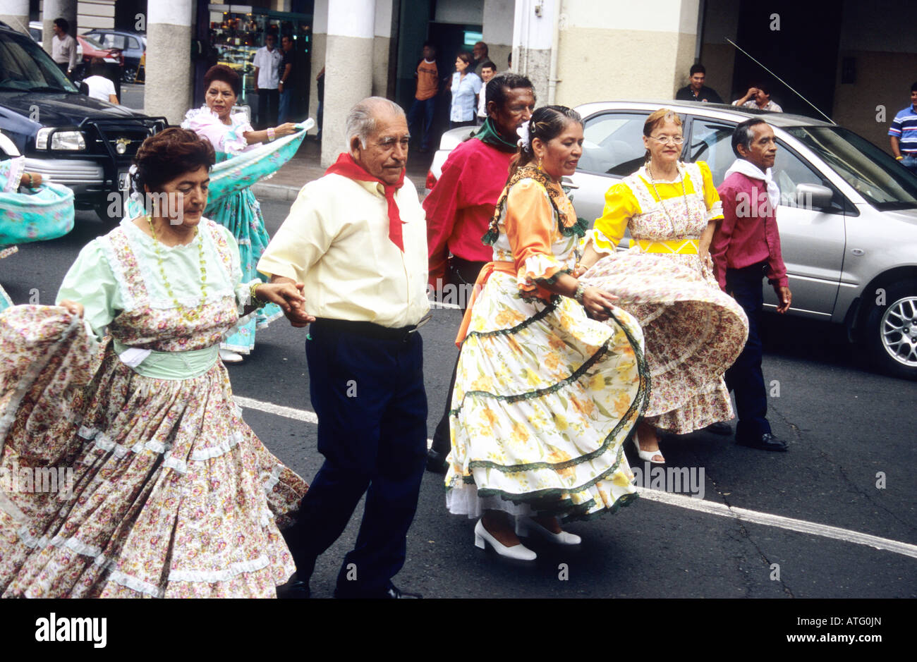 Procession de personnes, portant des vêtements de couleur vive, en dansant dans la rue à Guayaquil. L'Équateur. Banque D'Images