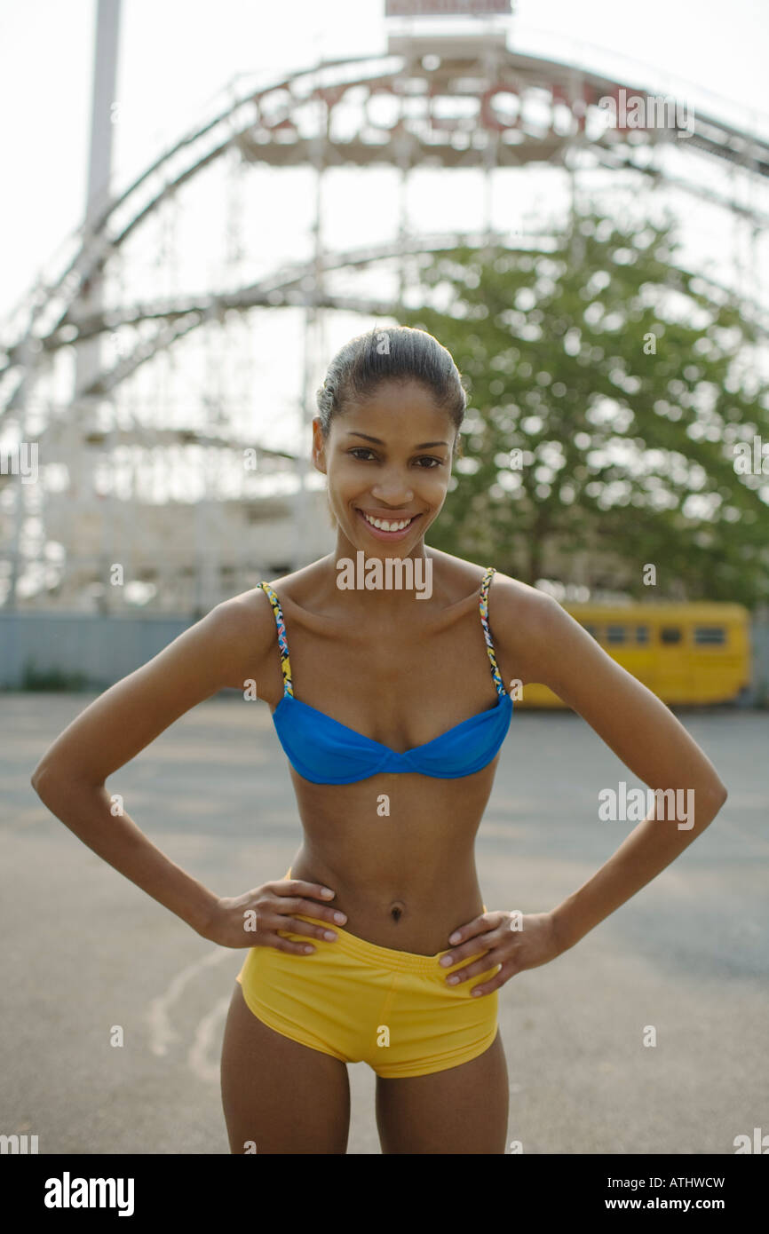 Jeune femme à Coney Island par un beau jour d'été avec le Cyclone roller coaster en arrière-plan Banque D'Images