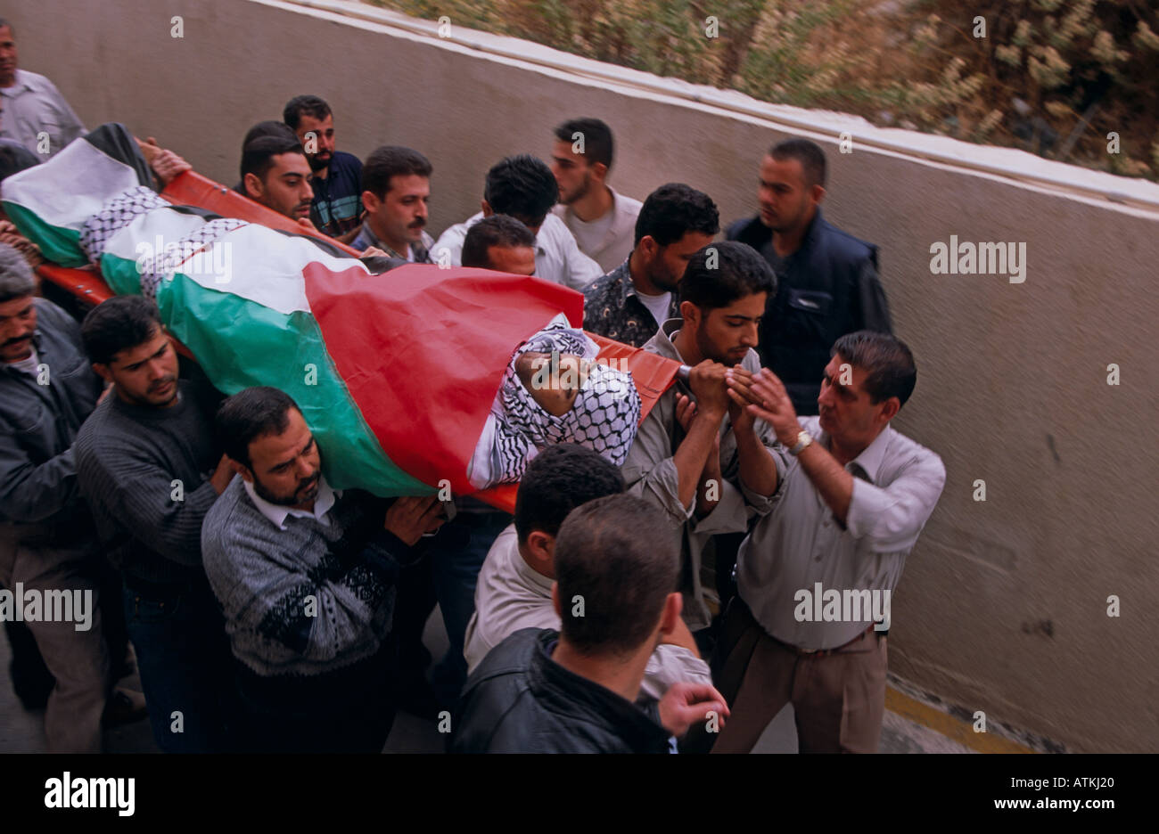 Hommes portant un corps enveloppé dans le drapeau de la Palestine Banque D'Images