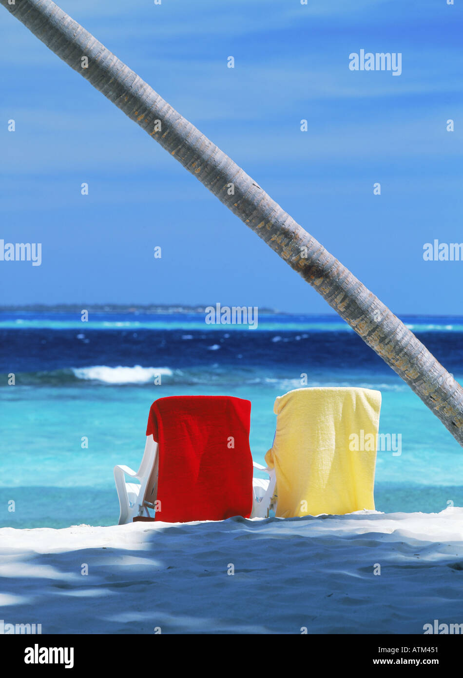Chaises de plage et serviettes sur sable à l'ombre de palmier Banque D'Images