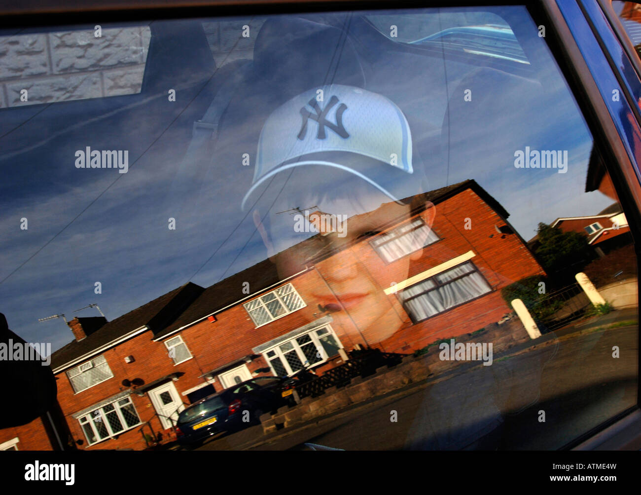 Un garçon de 13 ans assis dans une voiture, avec des maisons qui se reflète dans le verre.formant une image composite surréaliste. Banque D'Images