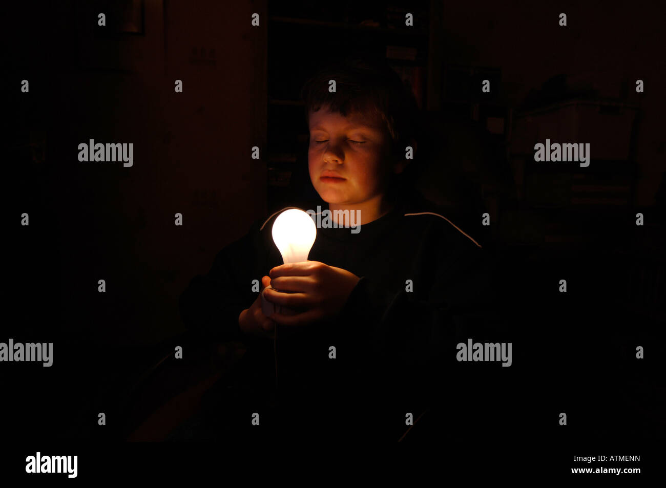 Un garçon de 13 ans tenant une ampoule lumineuse. Banque D'Images
