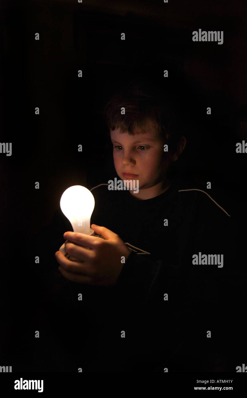 Un garçon de 13 ans tenant une ampoule lumineuse. Banque D'Images