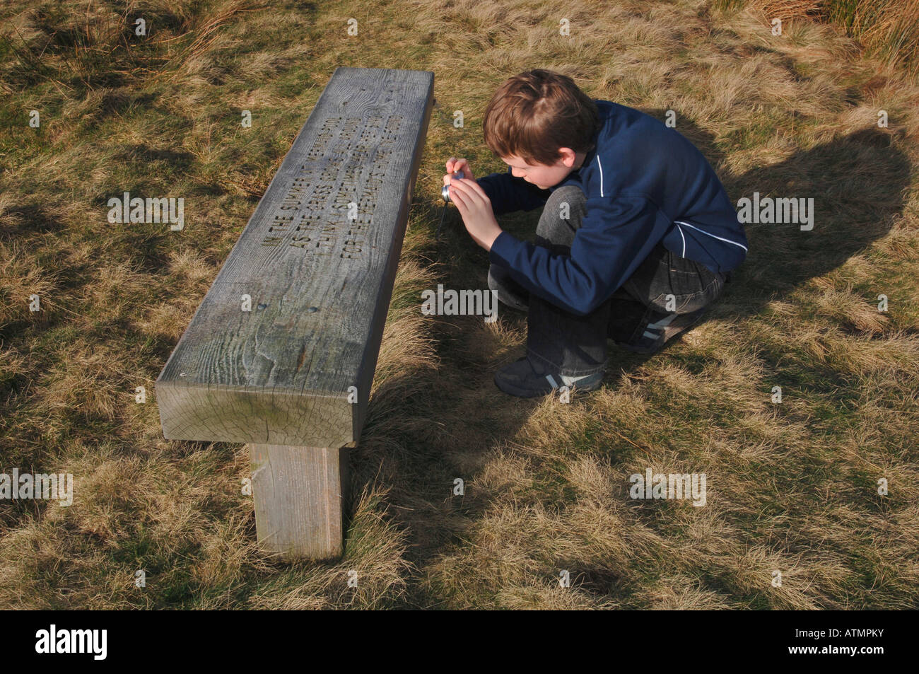 Un garçon de 13 ans de prendre une photo gros plan d'une assise en bois,à l'aide d'un petit appareil photo numérique de poche. Banque D'Images