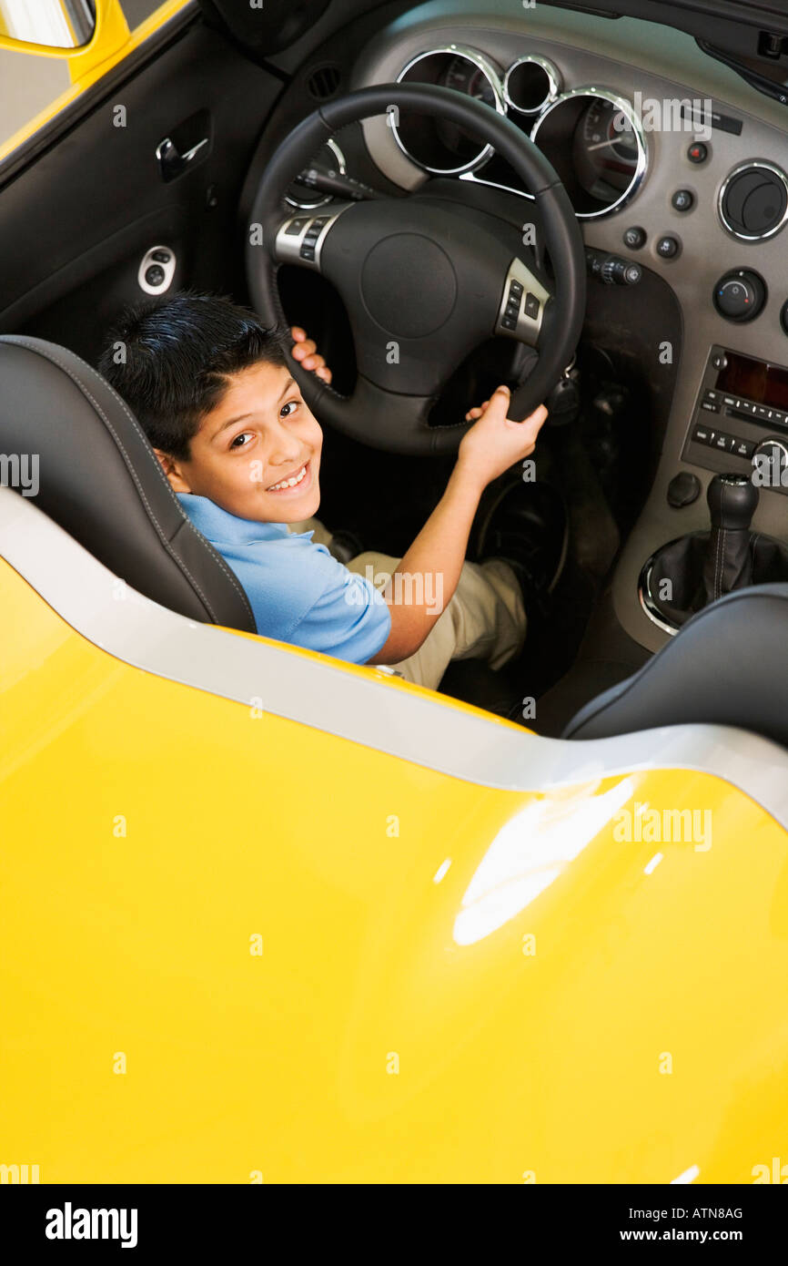 Hispanic boy sitting in new car Banque D'Images