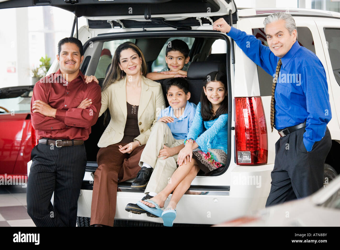 Family with salesman at car dealership Banque D'Images