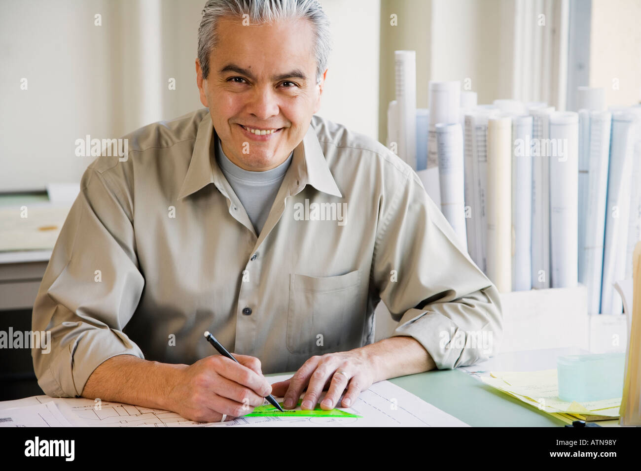 Hispanic male architect writing at desk Banque D'Images
