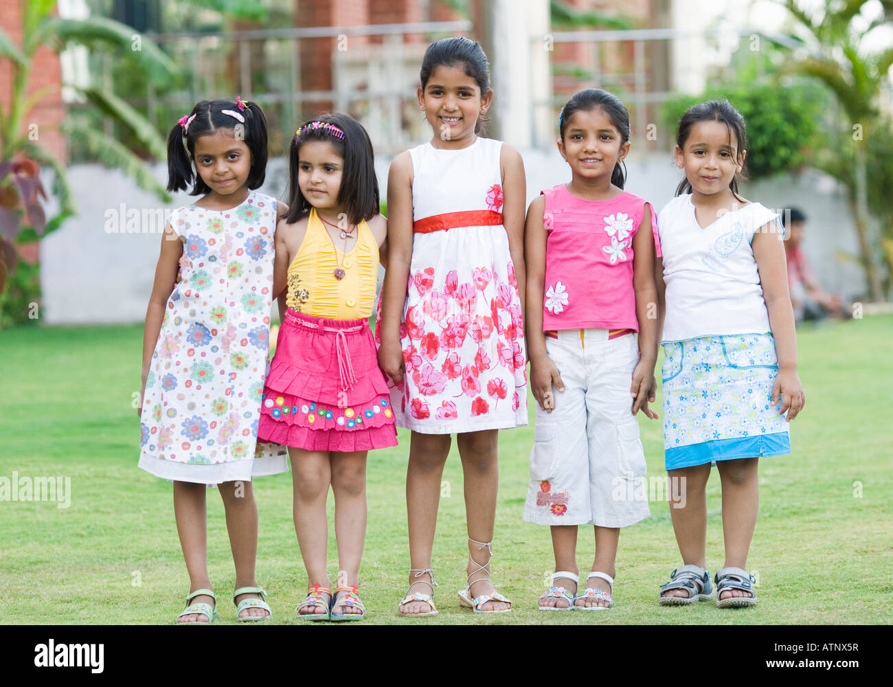 Cinq filles debout dans une pelouse et souriant Banque D'Images