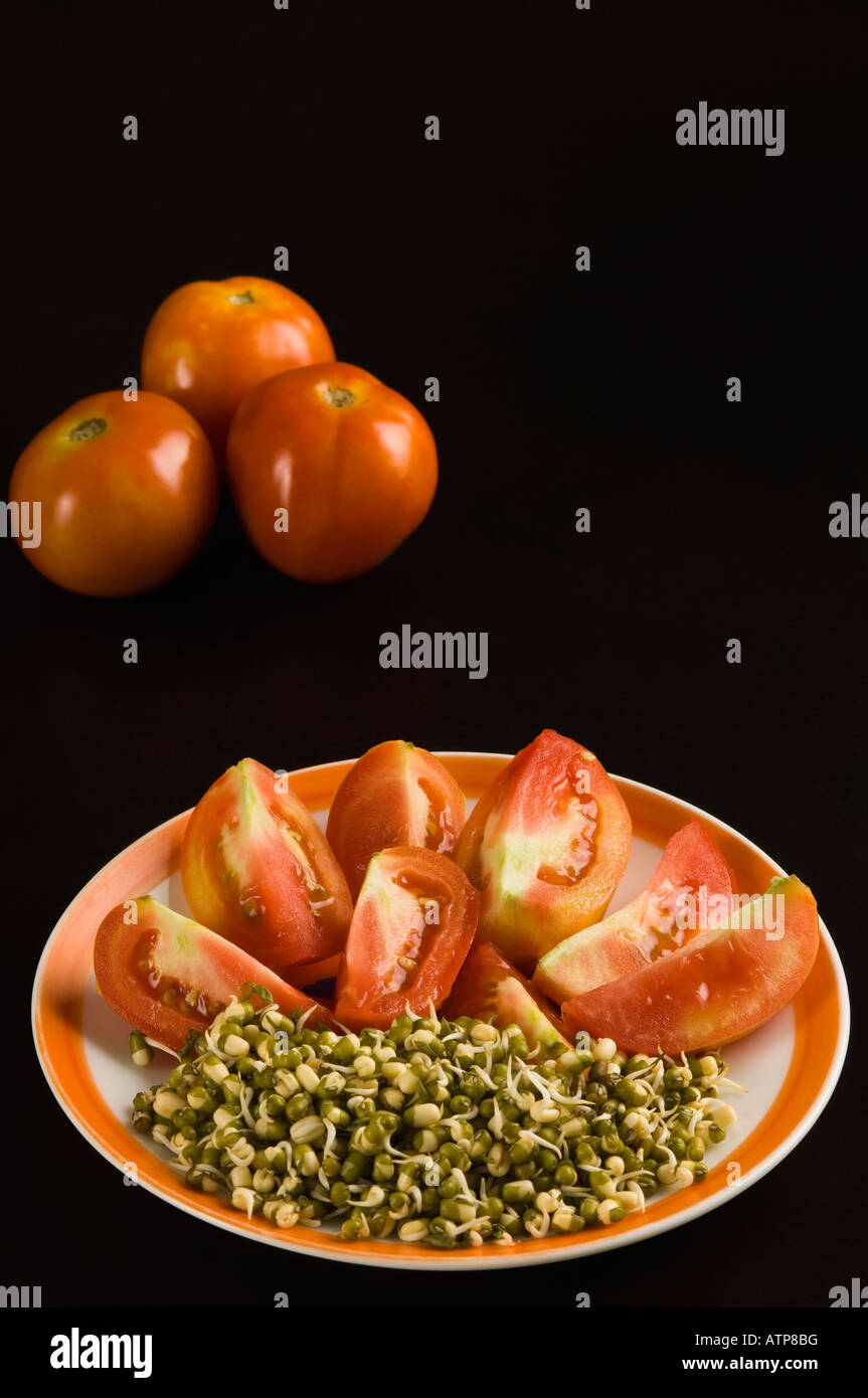 Close-up d'une plaque d'haricot germé avec tranches de tomate Banque D'Images