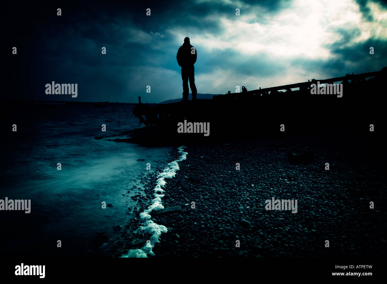 Homme debout sur un ponton de plage de Chesil dorset Banque D'Images