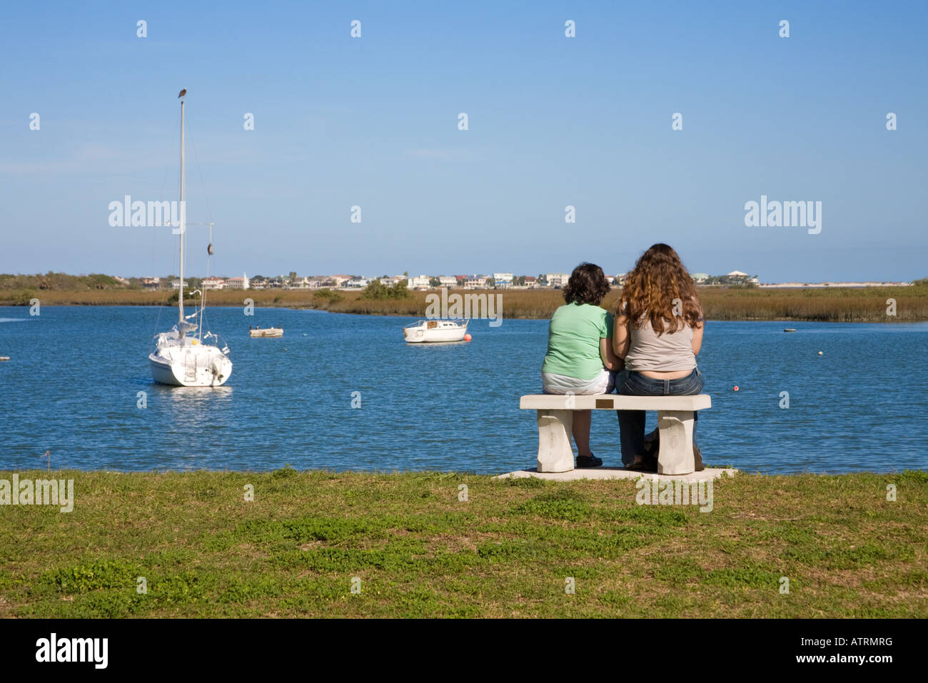 Deux jeunes filles assises sur un banc avec vue sur la rivière Matanzas à la Mission de Nombre de Dios, Saint Augustine, Floride, USA. Banque D'Images