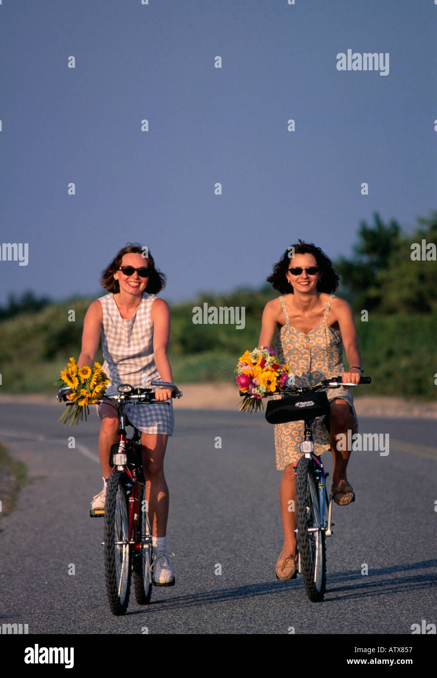 Deux jeunes de 25 à 30 à 35 ans les femmes assises sur vélo avec panier de fleurs, Southampton, Long Island, New York State, USA Banque D'Images