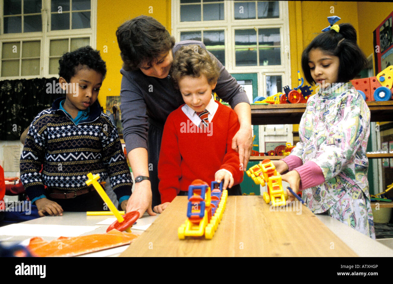 Un enseignant d'aider les enfants de l'école primaire dans la salle de classe Banque D'Images