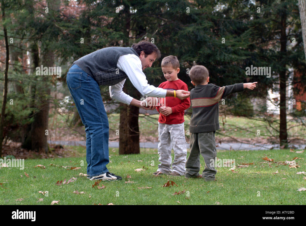 Les membres masculins de la famille élargie jouent au football dans leur cour avant le jour de Thanksgiving Banque D'Images