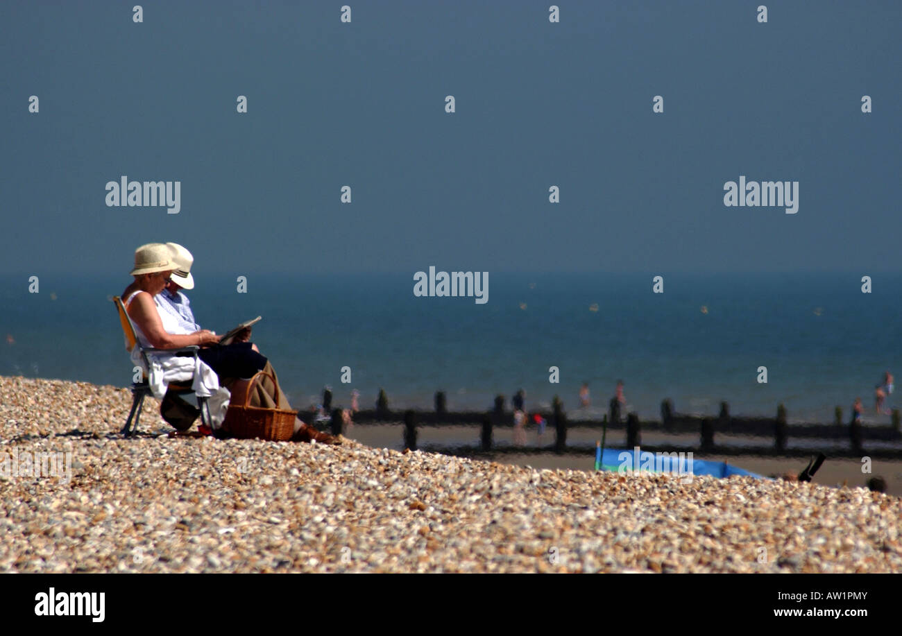 Un couple d'âge moyen de bronzer sur Littlehampton peach de galets sur la côte sud de l'Angleterre Banque D'Images