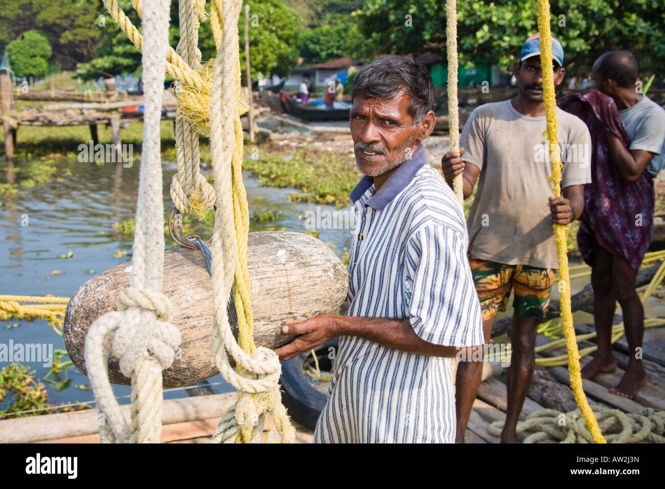 Les pêcheurs debout à côté des cordes et des filets de pêche chinois poids de pierre, fort Cochin, Cochin, Kerala, Inde Banque D'Images