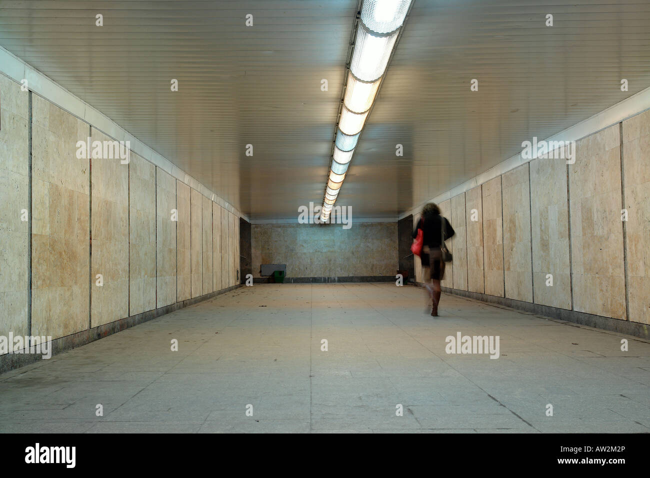 Femme avec sac rouge en passant par un passage souterrain Banque D'Images
