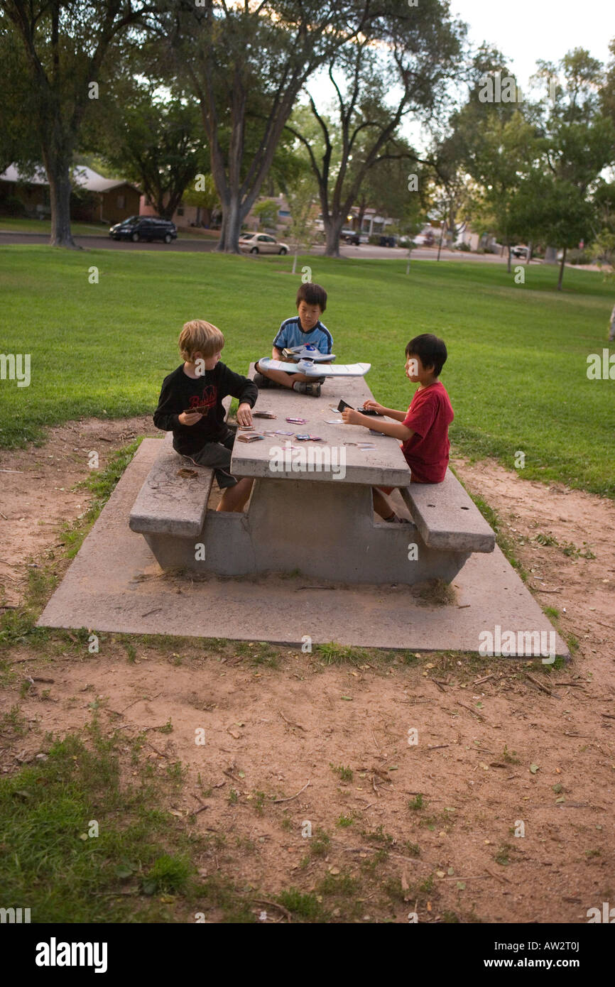 Trois jeunes garçons jouent au jeu de carte Yugioh au parc public, sud-ouest des États-Unis Banque D'Images