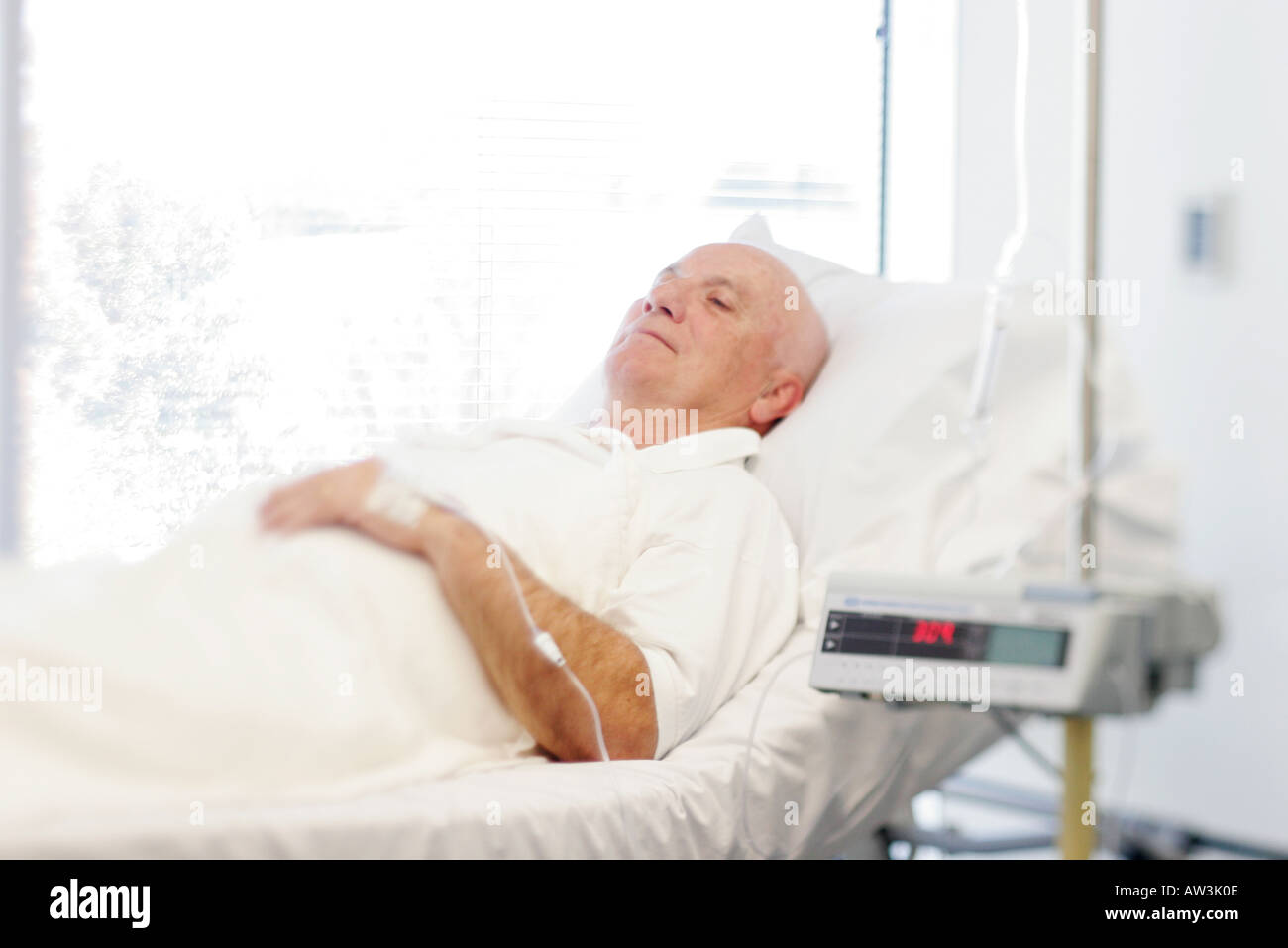 Un homme âgé se reposant sur lit ou gurney au cours de traitement de chimiothérapie à l'hôpital Banque D'Images