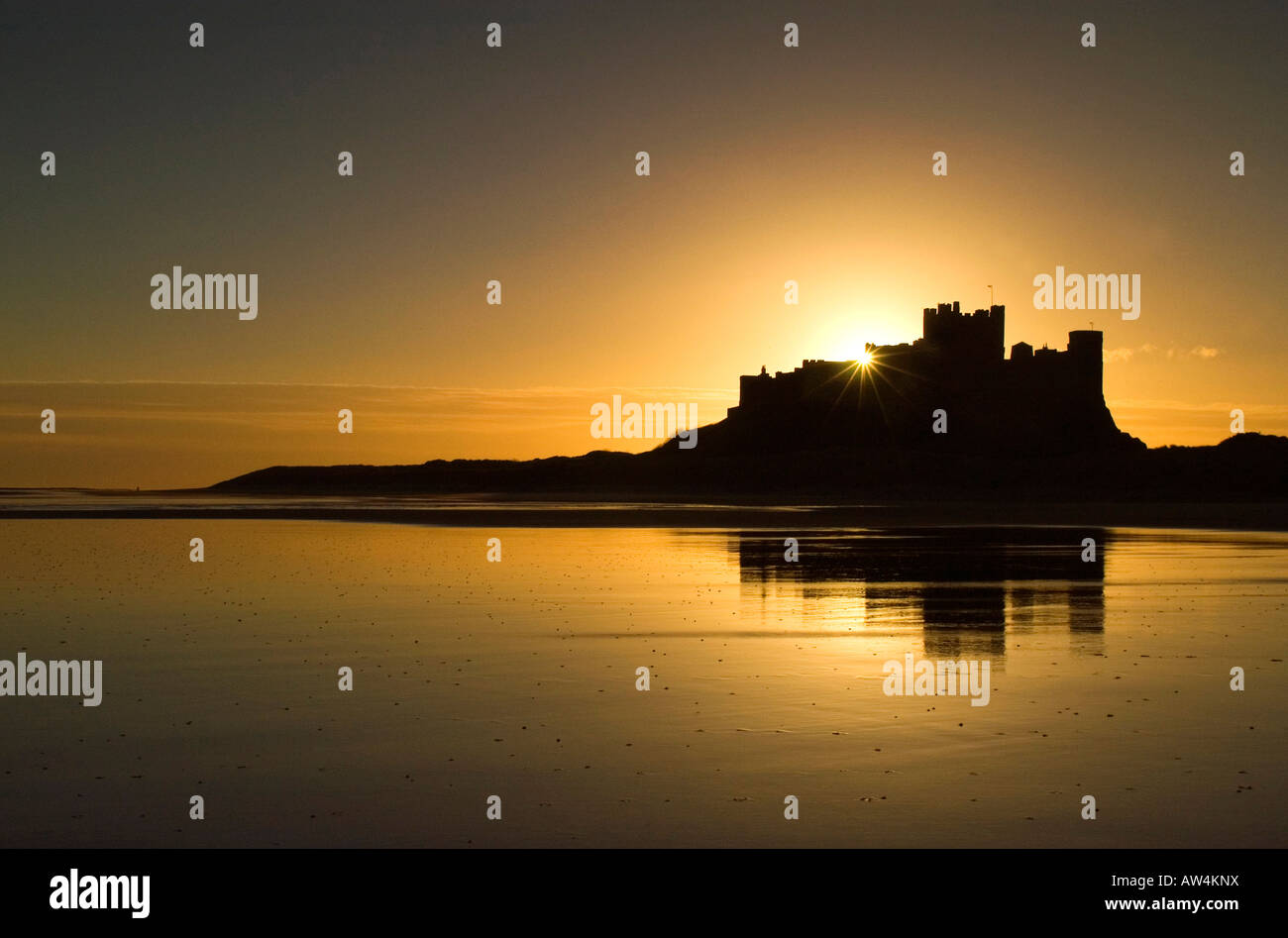 Château de Bamburgh au lever du soleil avec le château reflète dans le soleil du matin Banque D'Images