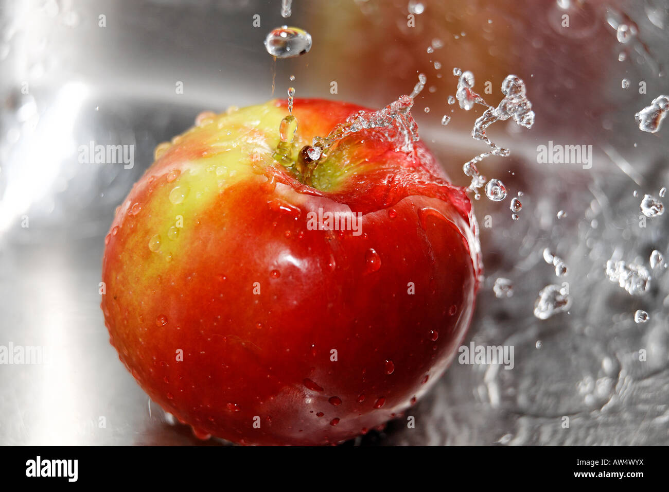 Des éclaboussures d'eau sur une pomme rouge mûre Banque D'Images