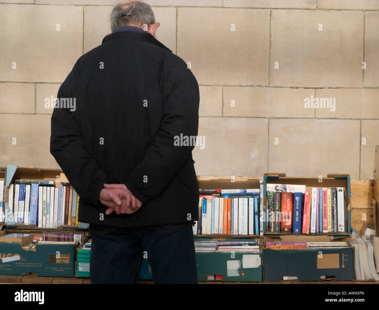 L'homme à la recherche de boîtes de livres de seconde main sur un marché de décrochage - Vue de derrière Banque D'Images