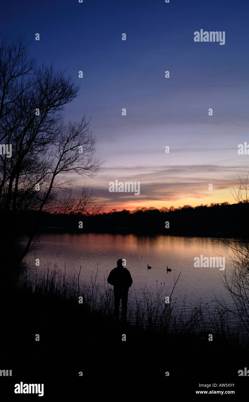 La silhouette de la figure d'un homme à temps le soir à Tittisworth,au réservoir dans le Staffordshire en Angleterre. Banque D'Images