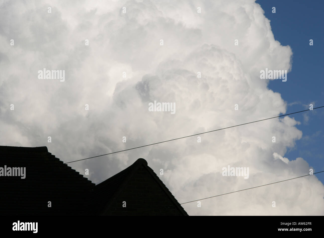 Cumulo nimbus nuages blancs au-dessus de la silhouette du toit avec câble de communication Banque D'Images