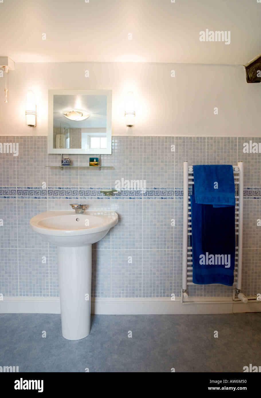 Salle de bains moderne avec lavabo AVEC MIROIR ET APPLIQUES ET sèche-serviettes avec serviettes bleu Banque D'Images
