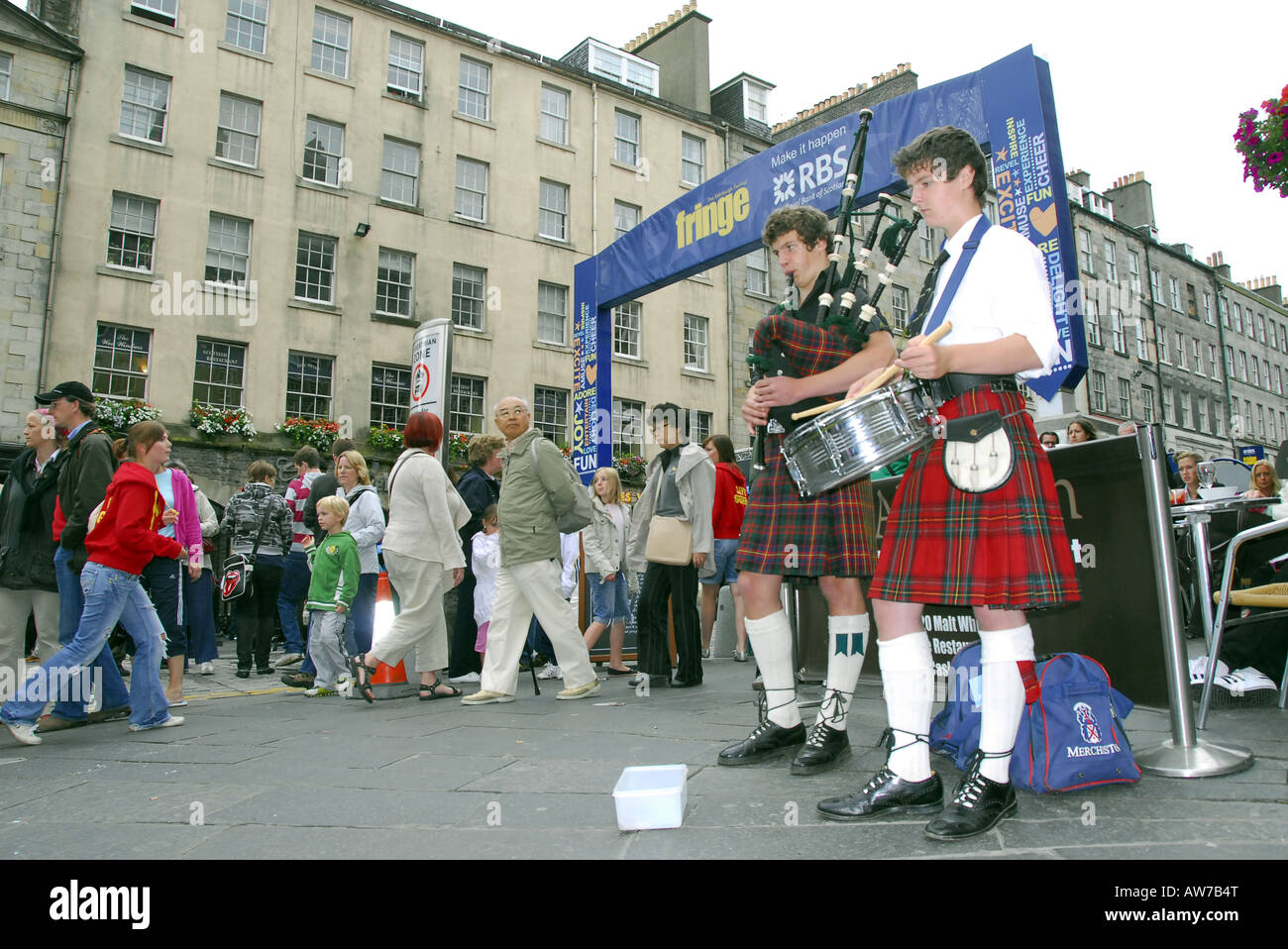 Deux jeunes hommes en costume national écossais jouant cornemuses et tambours en face de l'Edinburgh Fringe banner Banque D'Images