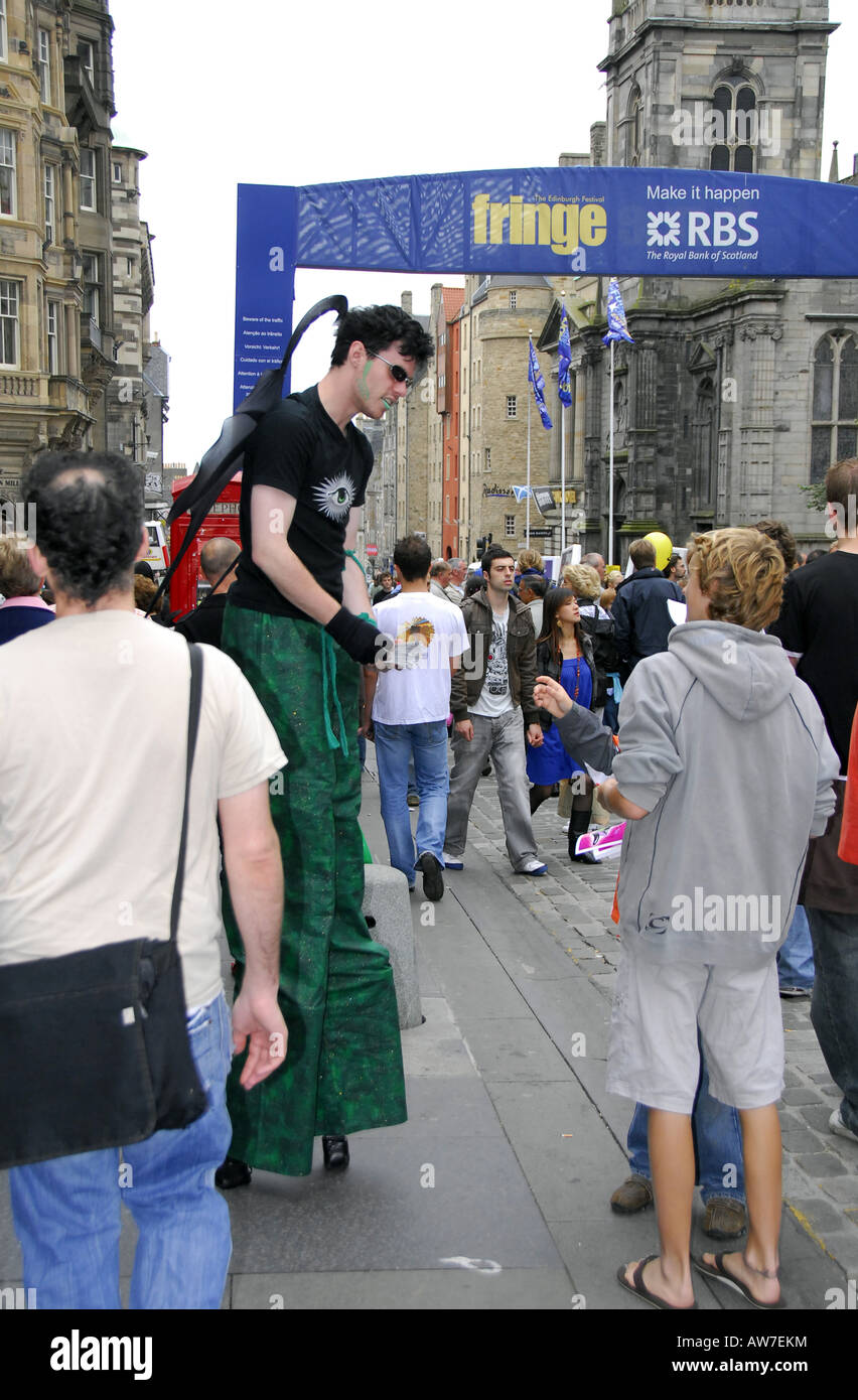 Artiste de rue sur échasses avec des foules en vertu de l'Edinburgh Fringe banner Banque D'Images