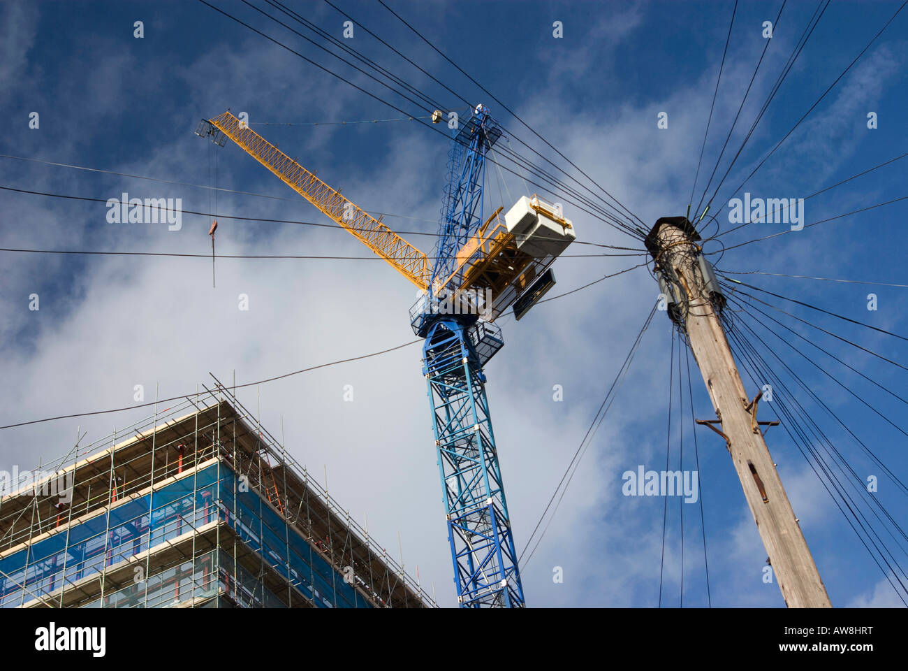 Les câbles téléphoniques qui se propagent au-dessous d'une grue et d'habitations Banque D'Images