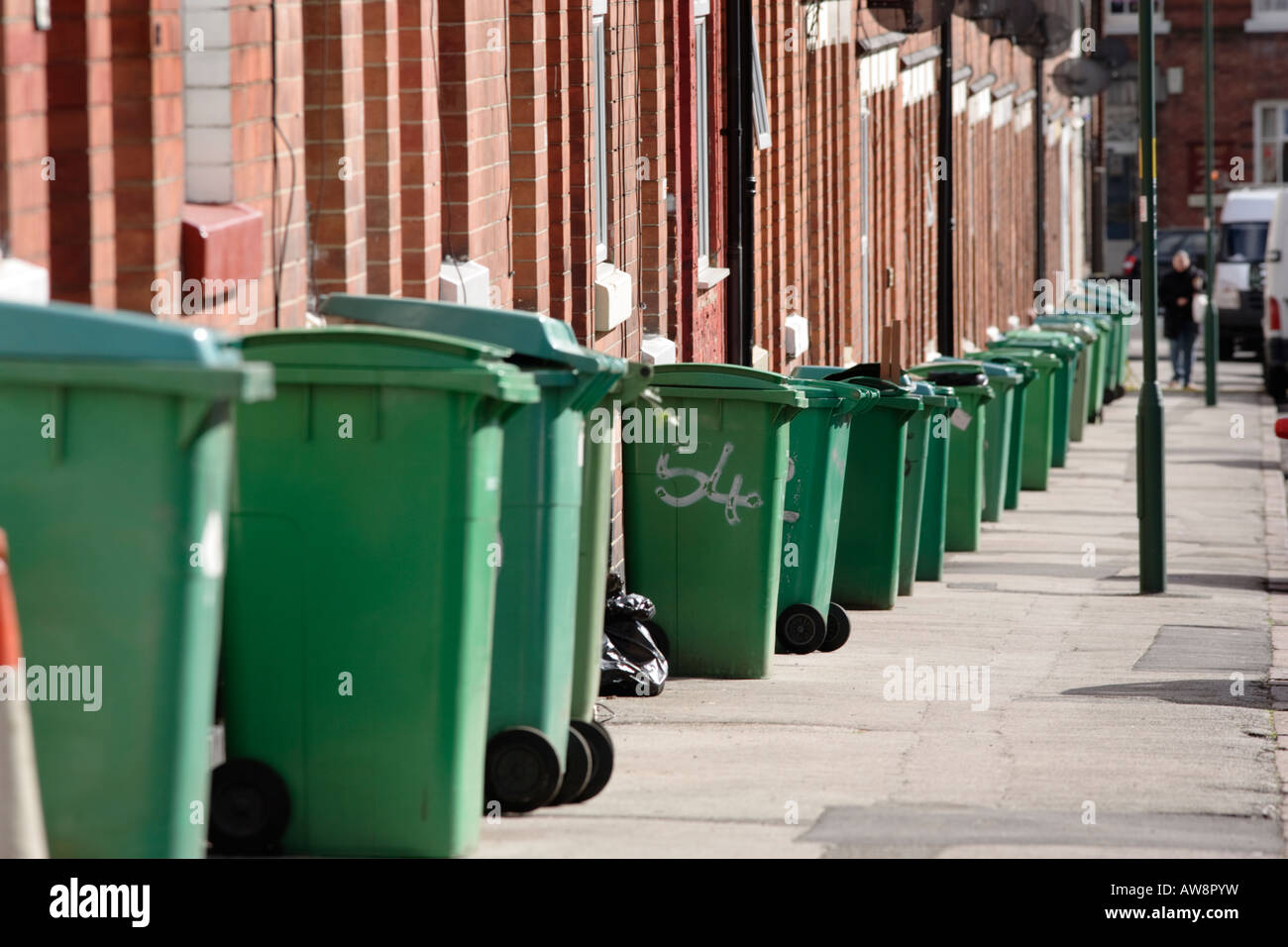 Une rangée de poubelles vertes en attente d'être recueillies sur un trottoir à Nottingham, Royaume-Uni Banque D'Images