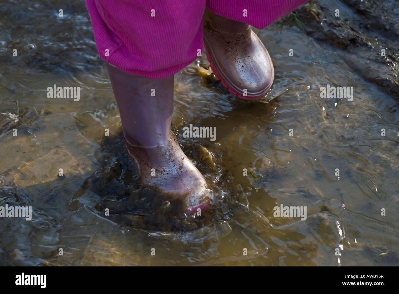 Image d'un enfant en rose bottes de s'éclabousser dans les flaques Banque D'Images