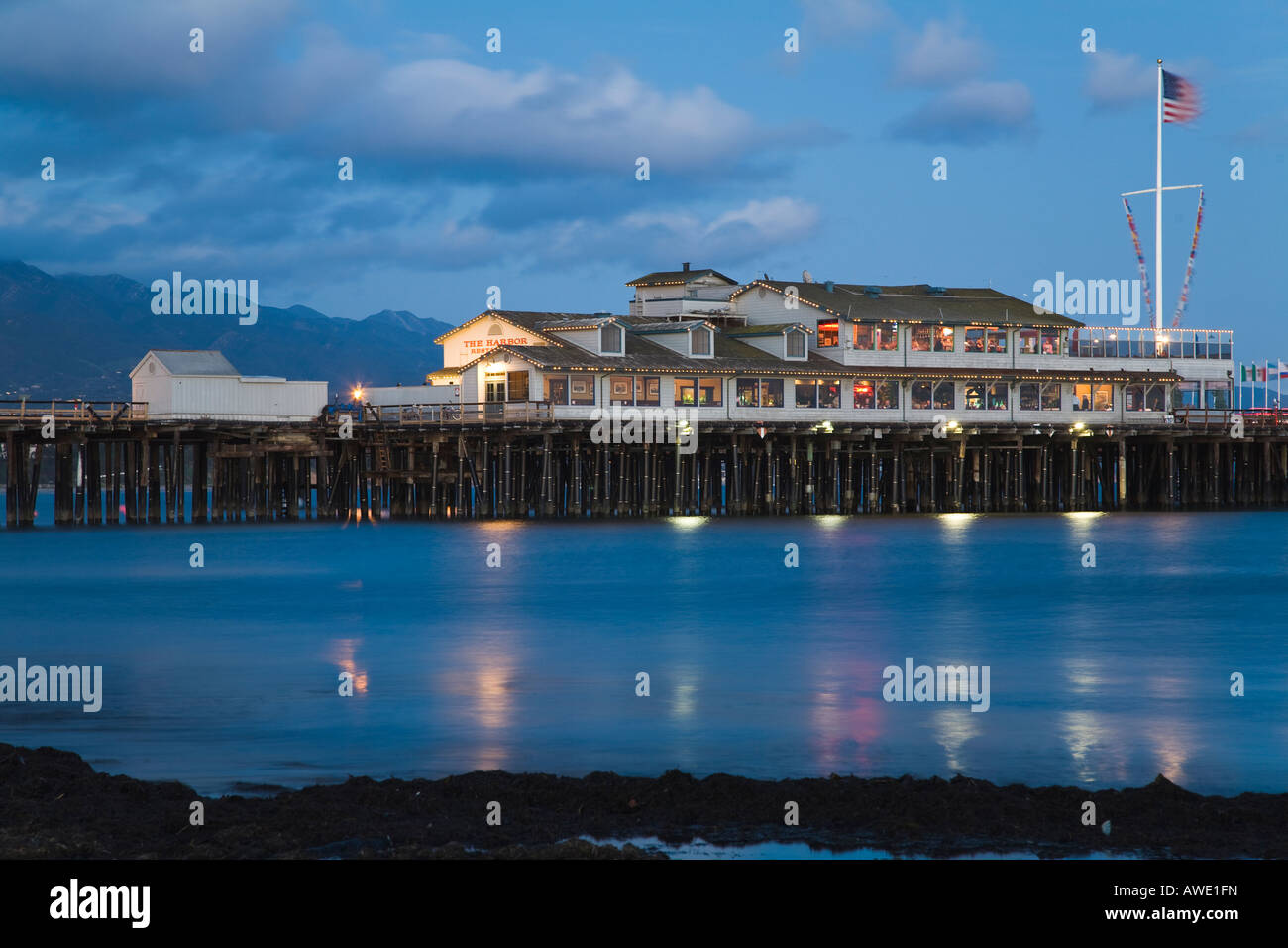 CALIFORNIA Santa Barbara Stearns Wharf Pier s'étendent dans l'océan Pacifique, restaurants et boutiques à la tombée de bâtiments et d'un drapeau Banque D'Images