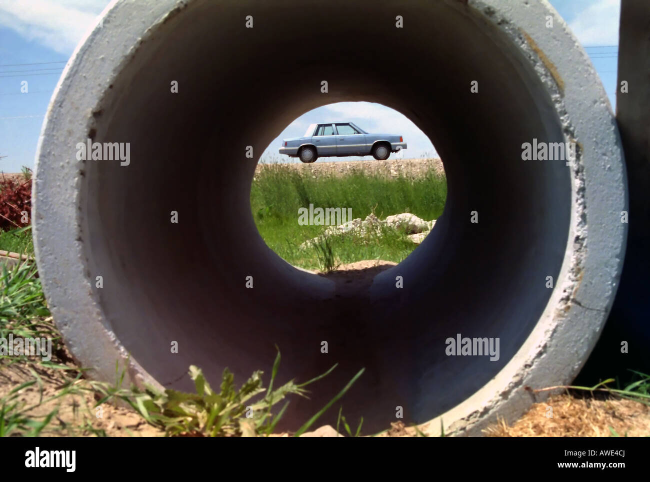 Ce gros tuyau de ciment frames une vieille auto de nombreux mètres. Le long tube de près, fait de la voiture look miniature. Banque D'Images