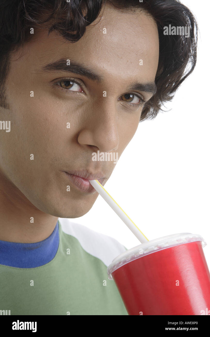 ANG200452 Teenage boy holding verre de boire des boissons gazeuses avec paille smiling MR 687T Banque D'Images