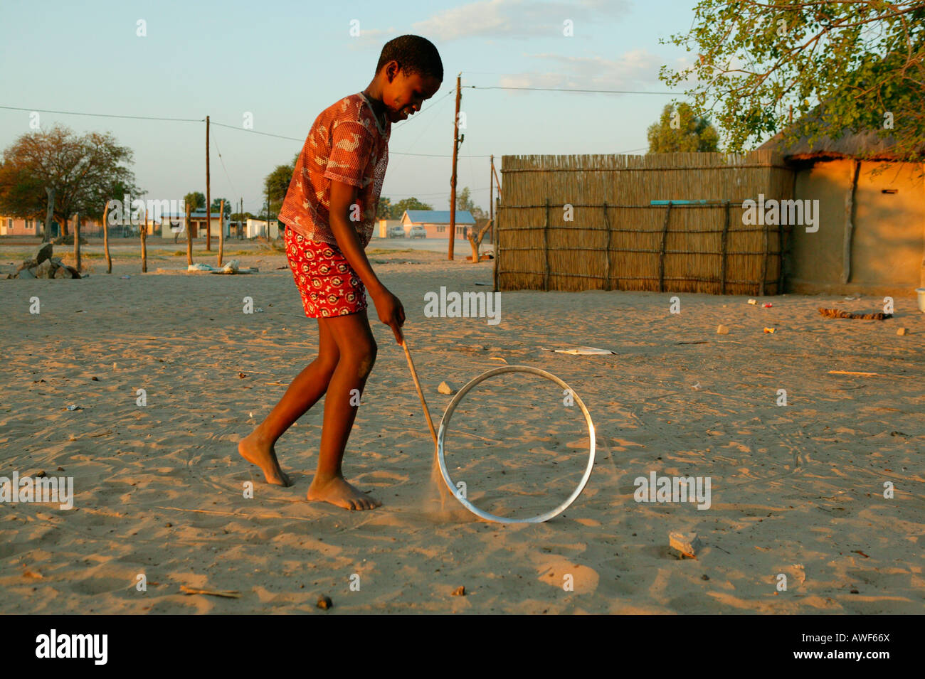 Garçon jouant avec jante sur la rue, Sehitwa, Botswana, Africa Banque D'Images