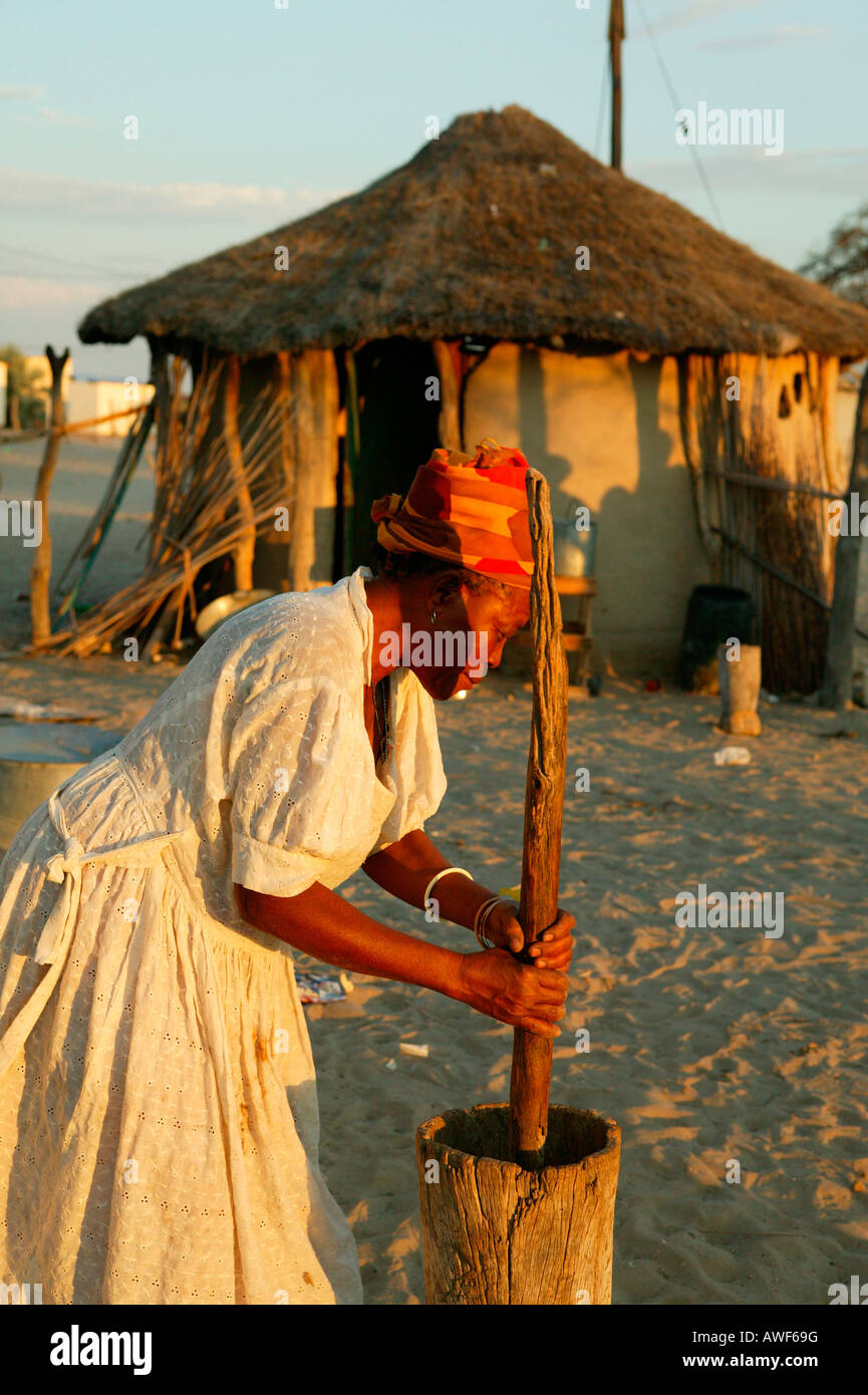 Vieille Femme battre le mil en face d'une hutte, ronde Sehitwa, Botswana, Africa Banque D'Images