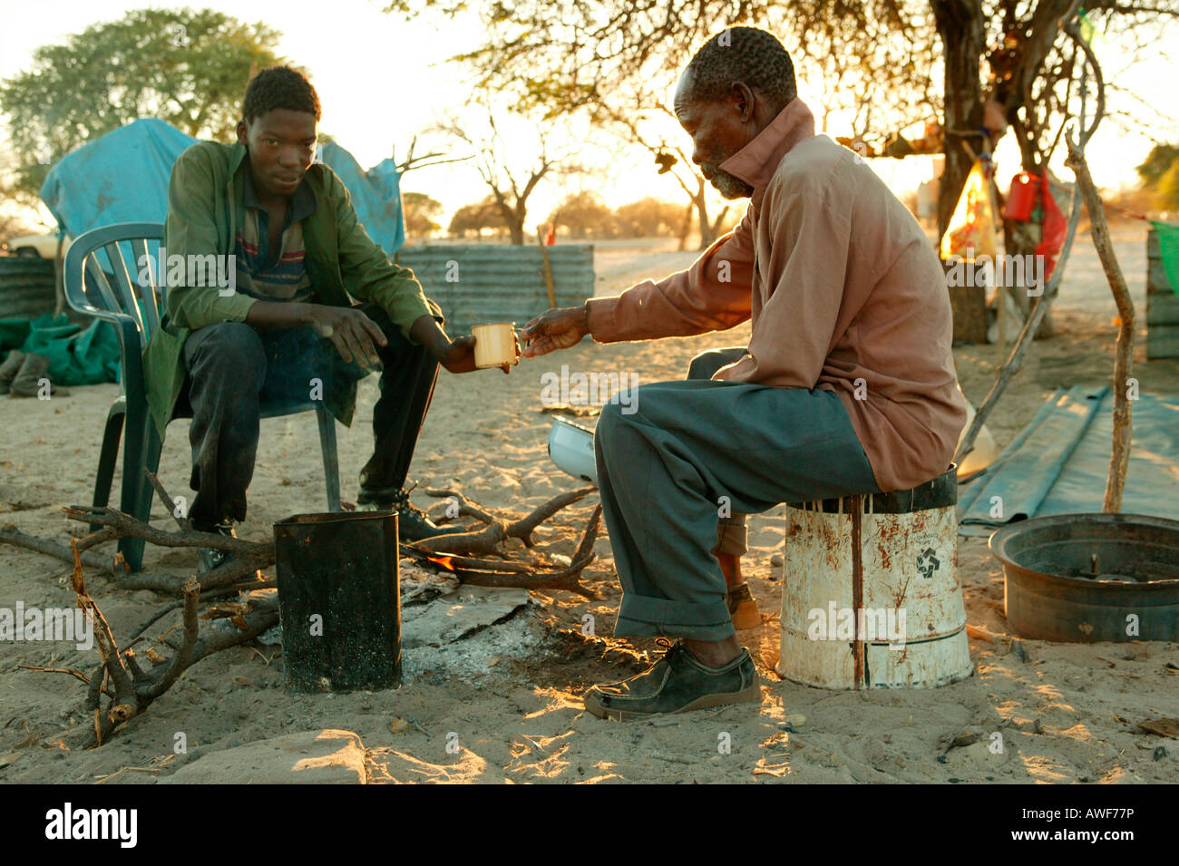 Deux hommes partageant petit-déjeuner à l'Cattlepost Bothatoga, feu de camp, Botswana, Africa Banque D'Images