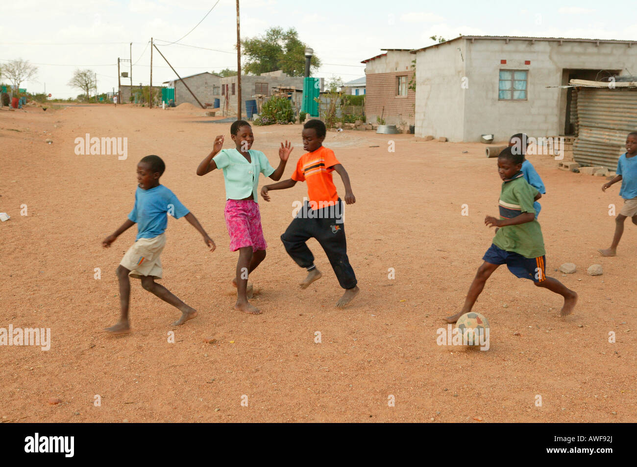 Enfants jouant au football sur chemin de terre, Sehitwa, Botswana, Africa Banque D'Images