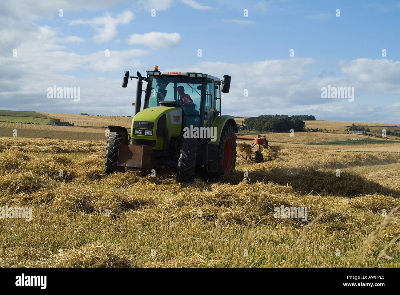dh séchage des champs de terre agricole TODHEAD POINT KINCARDINESHIRE tracteur épandage d'orge récolte de champs au royaume-uni les tracteurs verts récoltant en écosse Banque D'Images