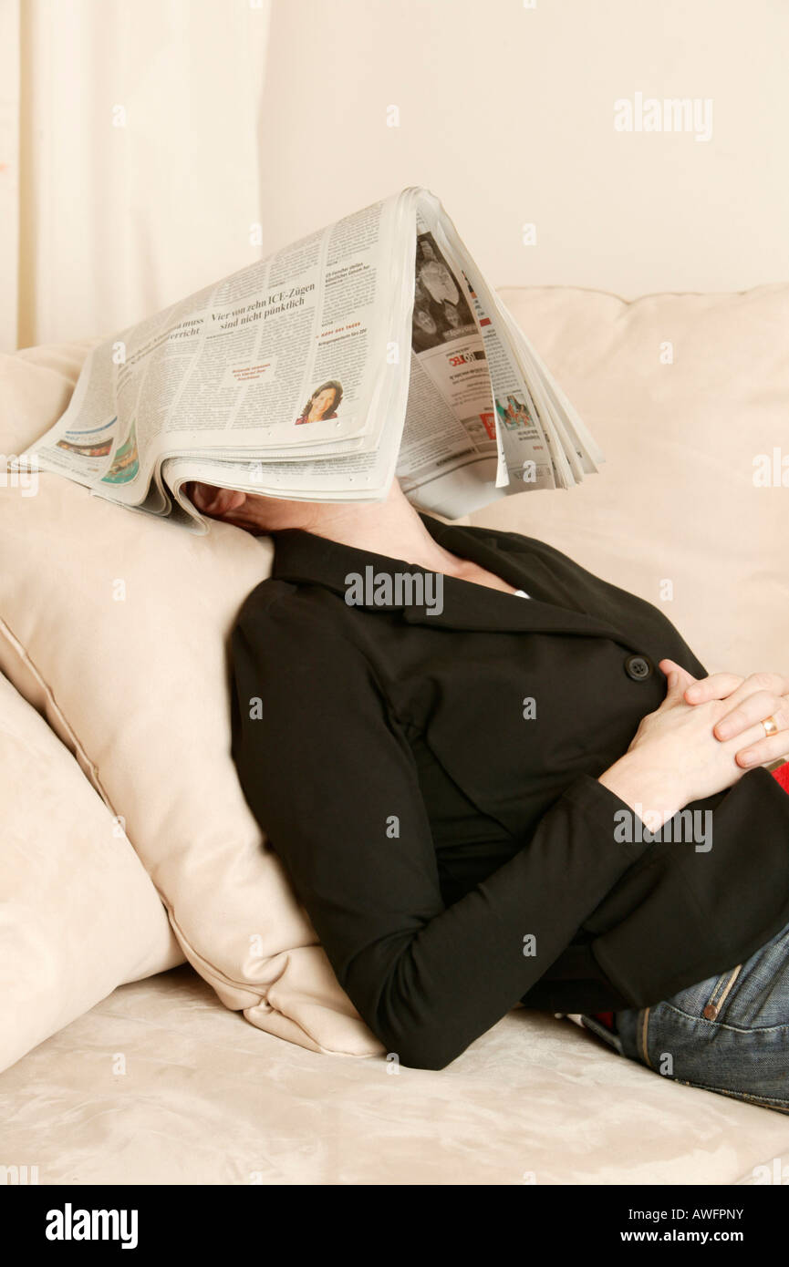 Femme d'âge moyen avec du papier journal sur son visage Banque D'Images